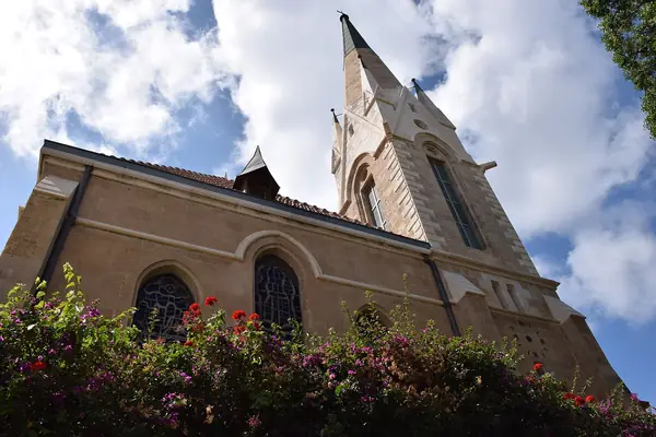 The spire of Immanuel Church above a flowering garden in the American-German Colony, Tel Aviv