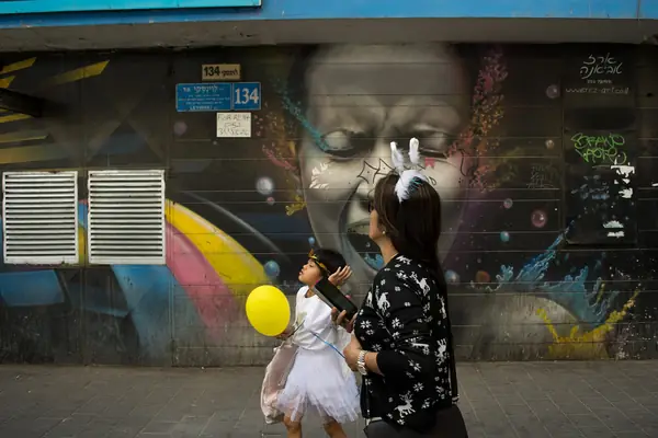 A large face mural along Levinski Street with passers-by in the Florentin quarter