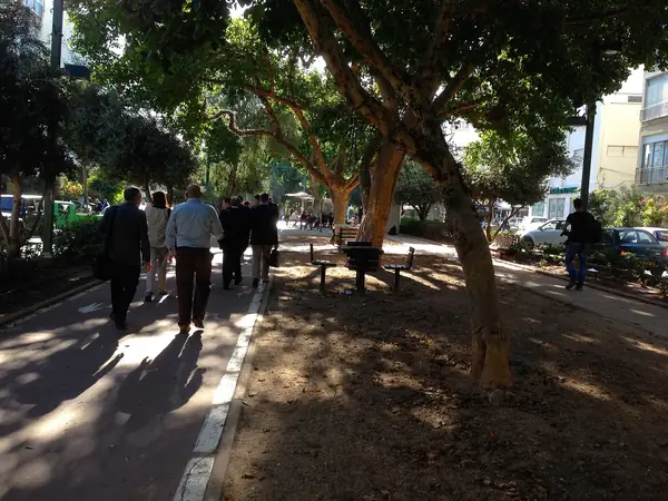Pedestrians strolling the tree-lined central walkway of Ben Gurion Boulevard in the Old North